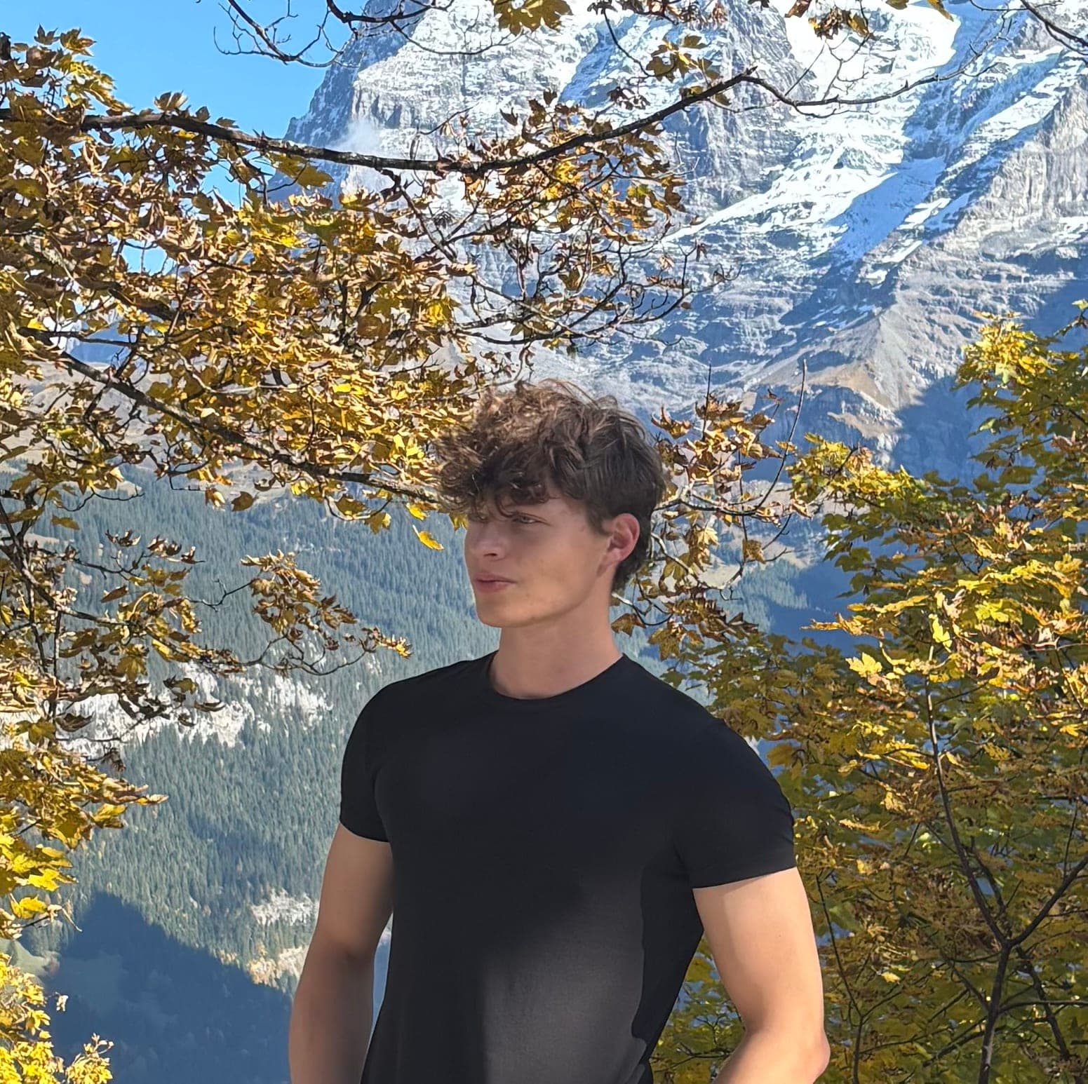 Walking green flag Richard Kocanda in a black T-shirt under autumn leaves in front of a snowy mountain