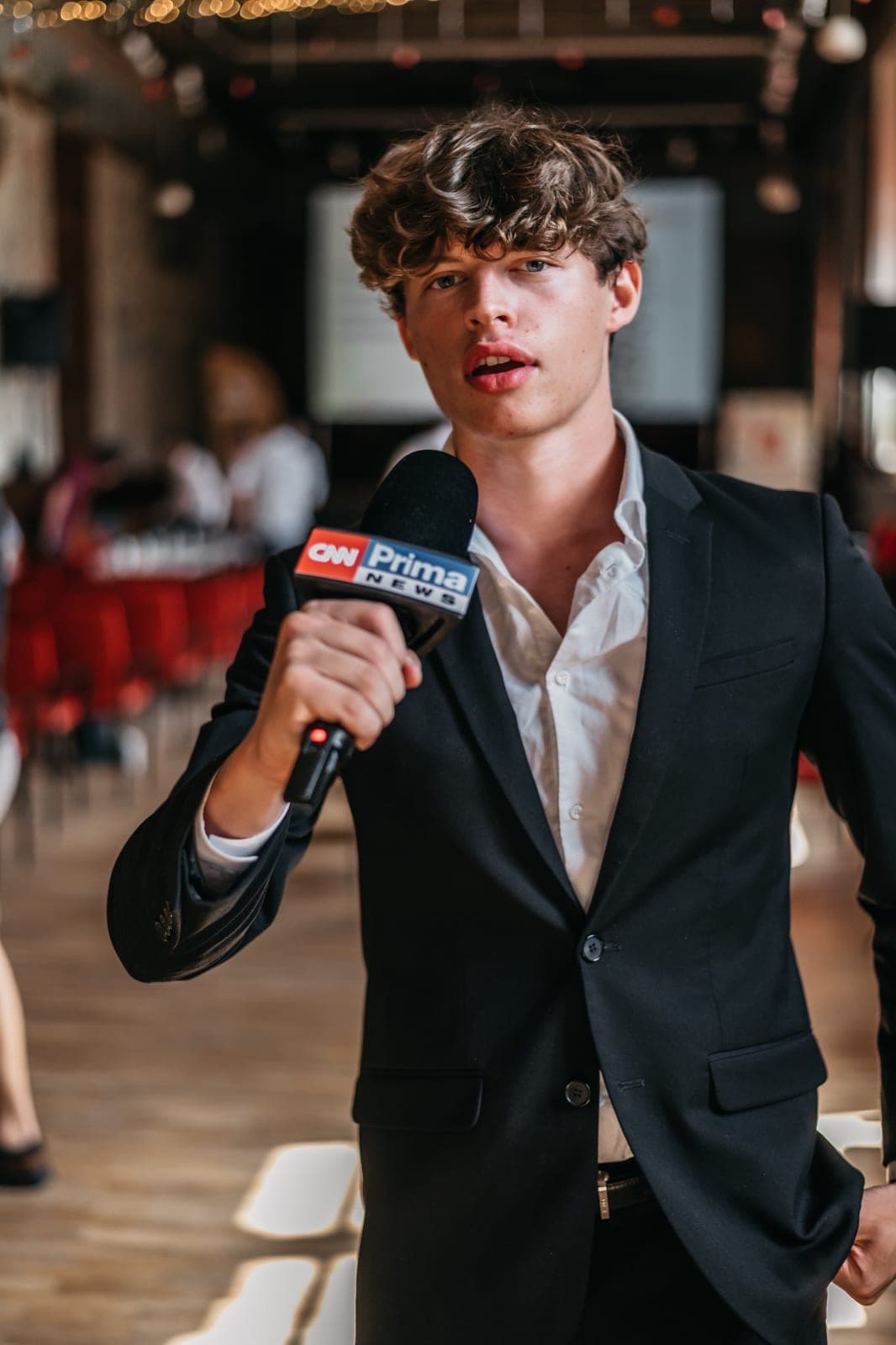 The walking green flag in Prague in a black suit holding a CNN Prima News microphone